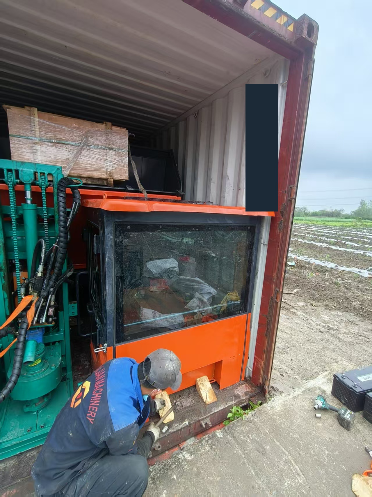 Equipment, machine components and a wrapped wooden crate positioned inside a shipping container during packing