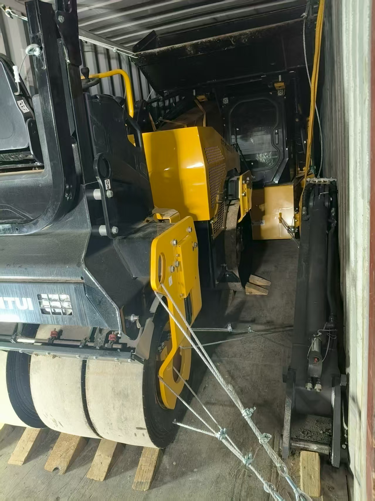 Shantui road roller and skid steer loader inside a shipping container with timber blocking and wire lashings